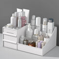 Desktop cosmetic storage box with drawers holding makeup and skincare on a vanity.